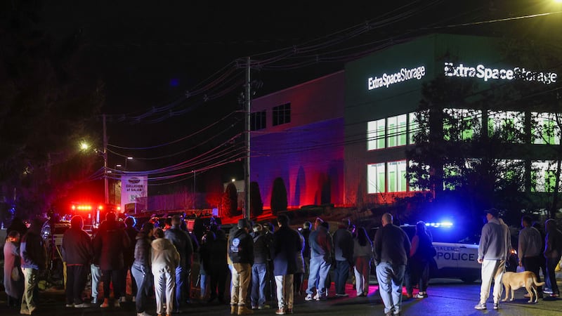 Personas se reúnen afuera de un almacén donde se encontró muerto a un sospechoso del tiroteo...