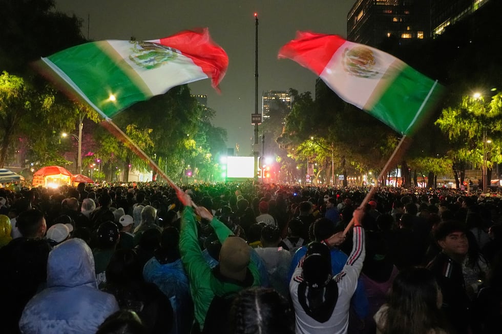 Mexican fans wave flags as they watch the World Cup round of 32 soccer match between Mexico...