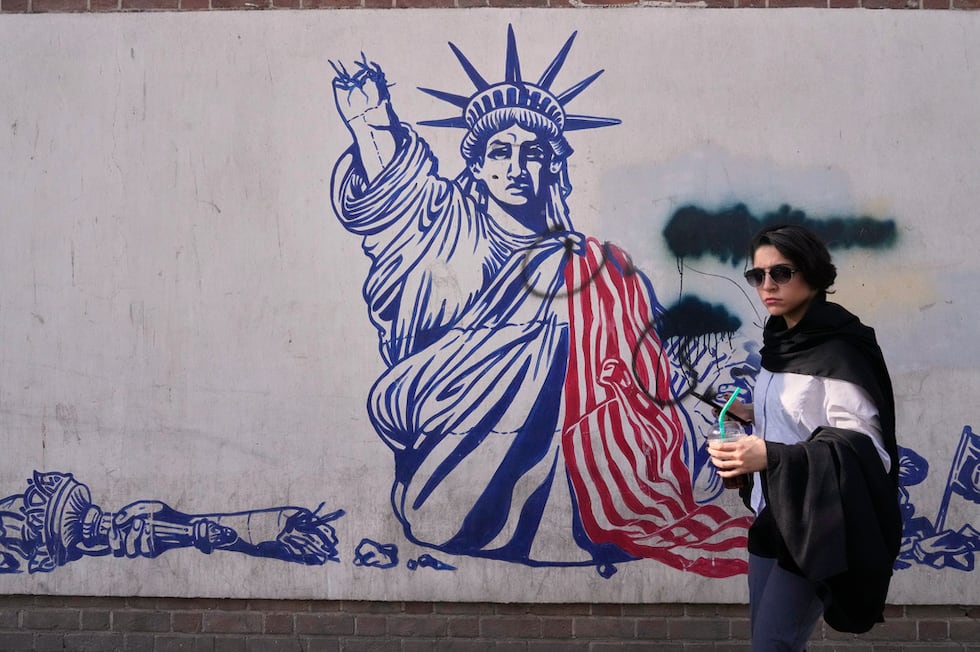Una mujer pasa junto a un mural antiestadounidense en la pared de la antigua embajada de...