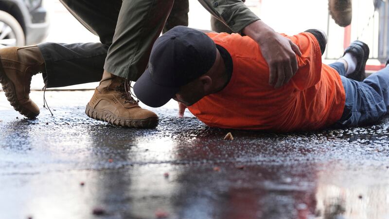Un hombre es detenido por agentes de inmigración en un negocio de lavado de autos el viernes...