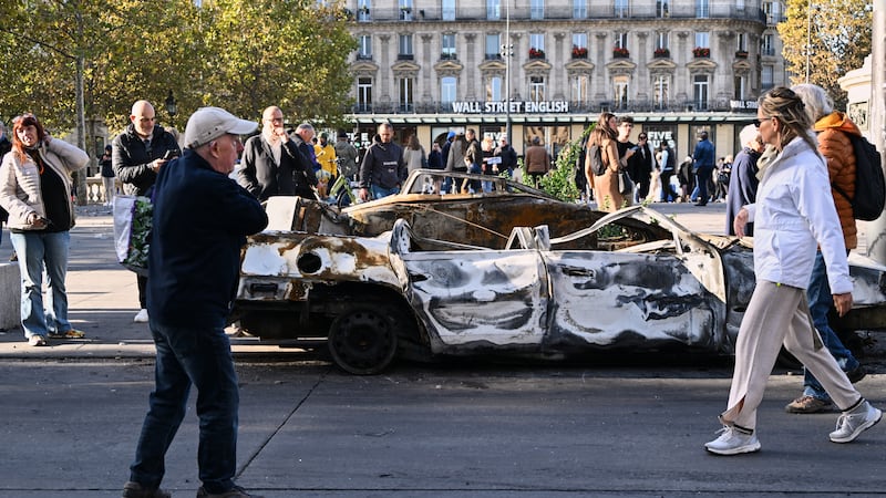 Gente mira a un auto calcinado en Place de la Republique el día después de una manifestación...