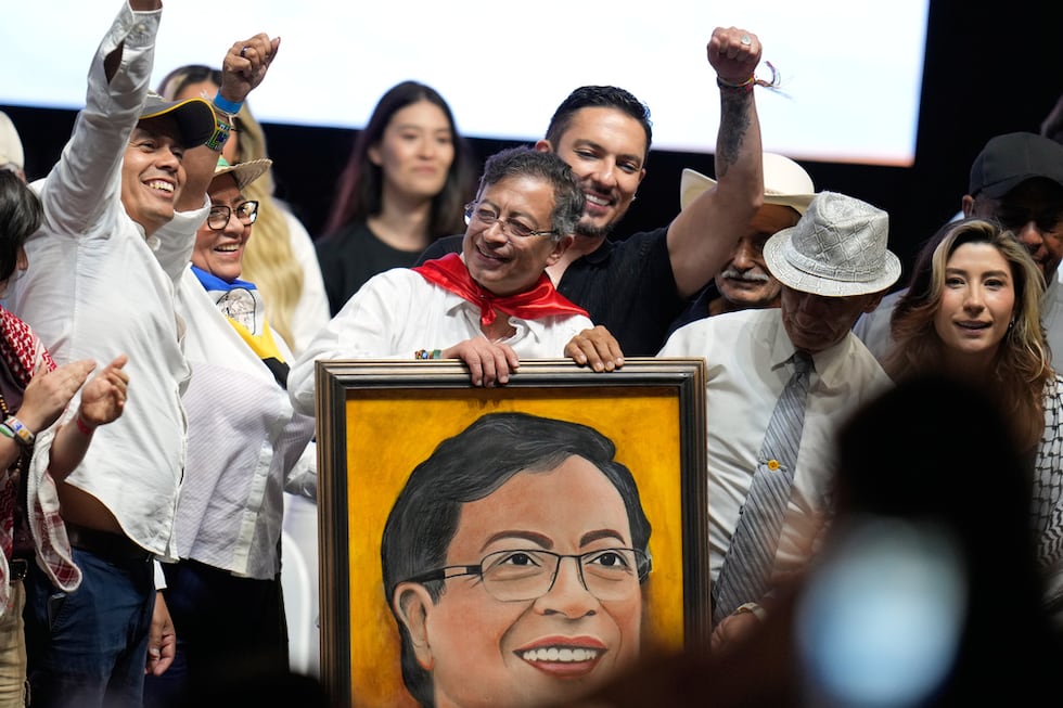 El presidente colombiano Gustavo Petro sujeta un retrato que un partidario le otorgó en un...